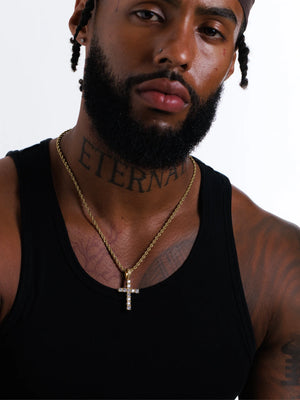 Man wearing the gold stone set cross pendant on a 3mm rope chain with a black vest