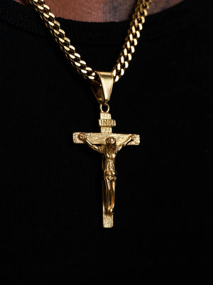 Close up of the gold filled INRI crucifix pendant and 4mm Franco chain links against a black top