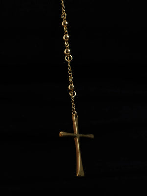 Detail of the tapered cross at the end of the rosary bead drop against a dark background