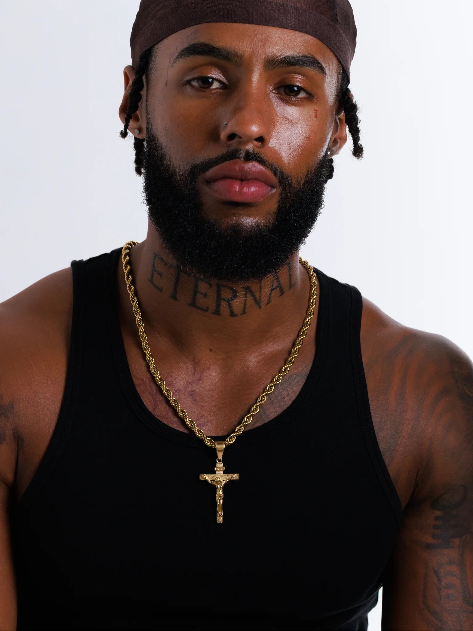 Man wearing the gold filled INRI crucifix pendant on a 6mm rope chain with a black vest