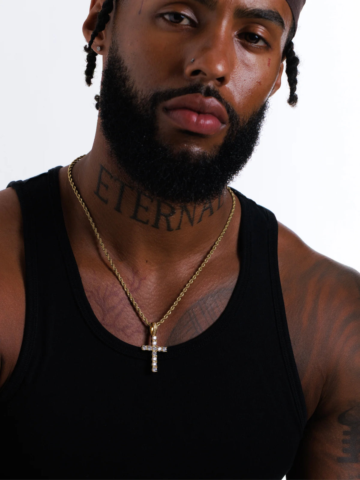 Man wearing the gold stone set cross pendant on a 3mm rope chain with a black vest
