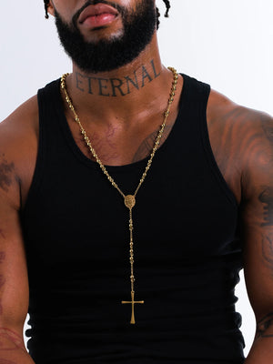 Man wearing the gold filled rosary bead necklace with a black vest, cross hanging mid chest