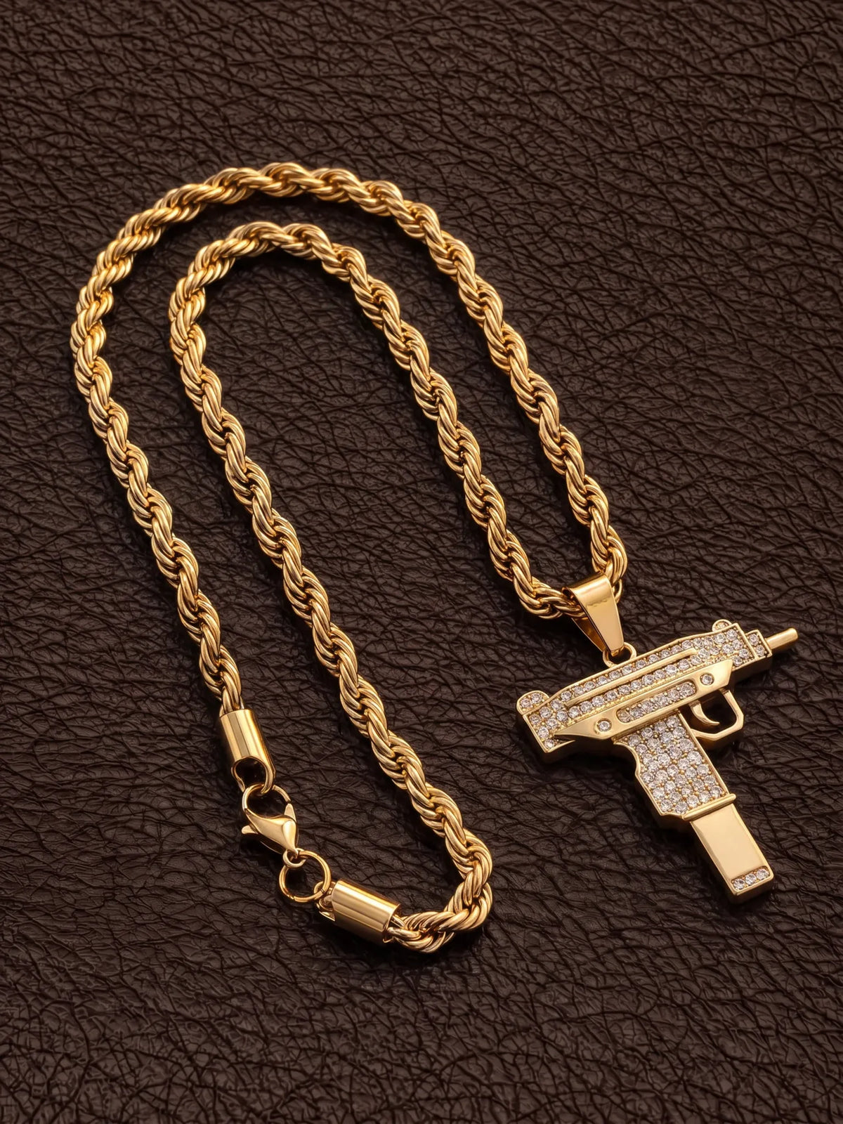 Gold filled uzi pendant on a 6mm rope chain laid out on dark leather with the clasp visible