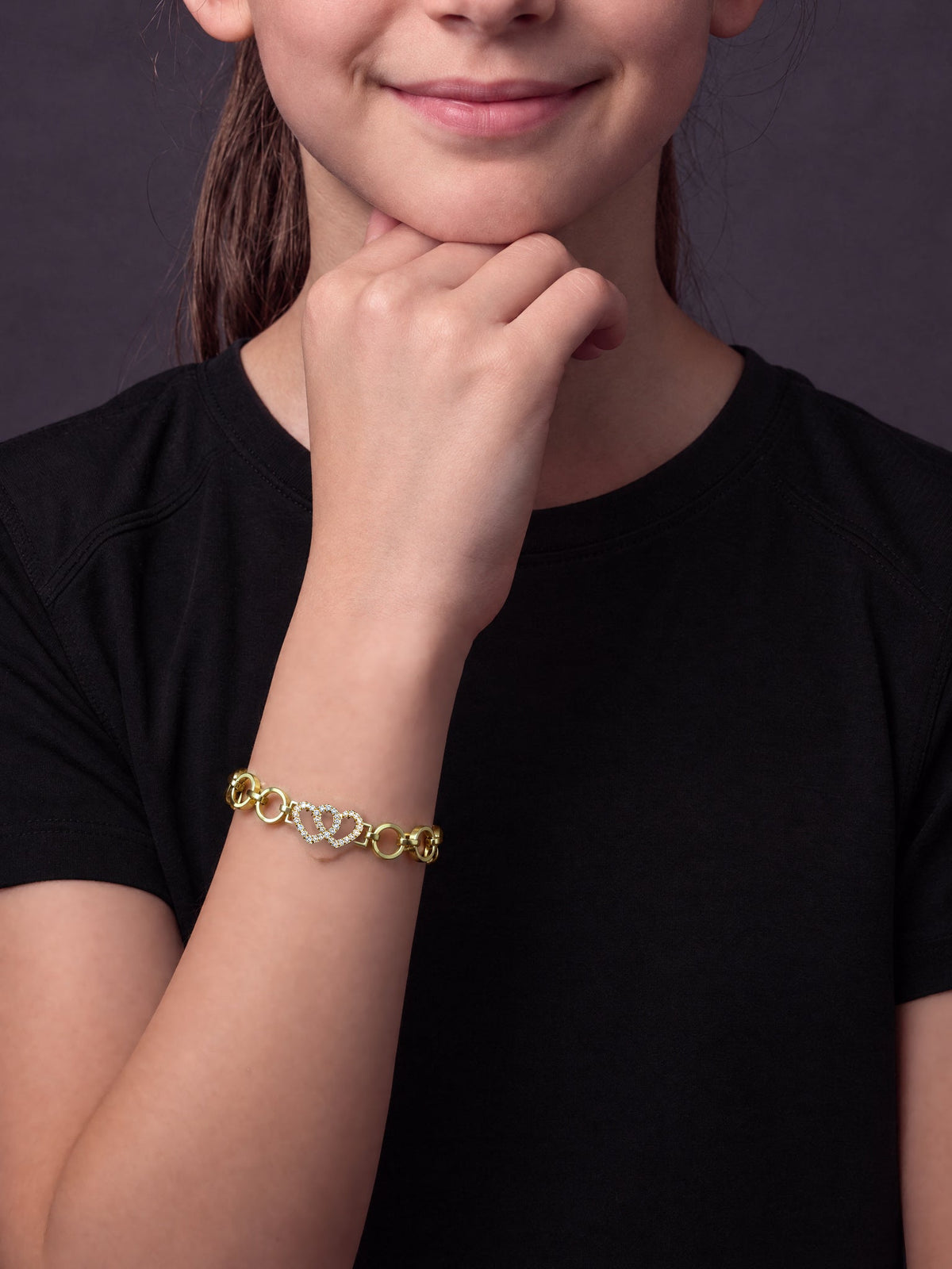 Girl resting her chin on her hand wearing the double love heart charm belcher bracelet