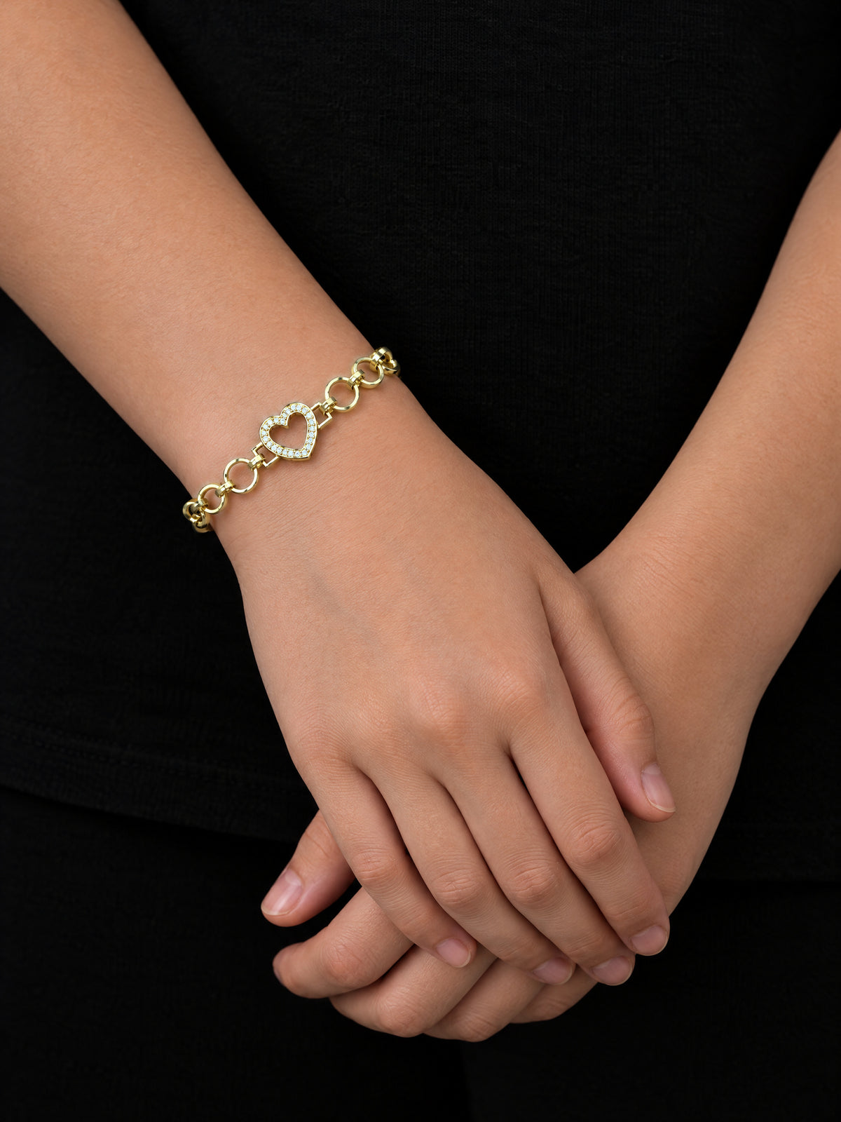 Girls Love Heart Charm Belcher Bracelet Gold Filled on a girl's wrist, hands folded